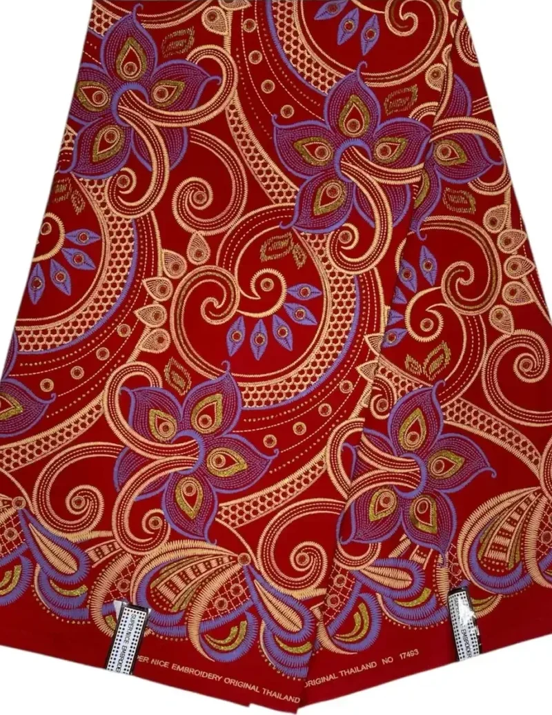 Vêtement traditionnel en wax africain avec motifs floraux colorés, principalement rouge, violet et or.